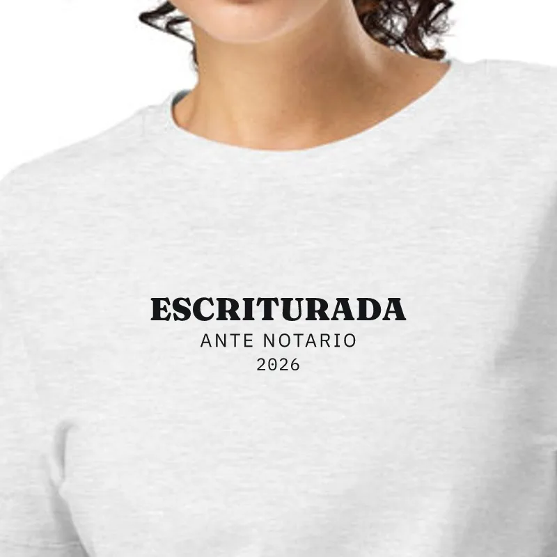 Dona amb samarreta gris jaspiat, enquadrament al segell: ESCRIPTURADA · DAVANT DE NOTARI