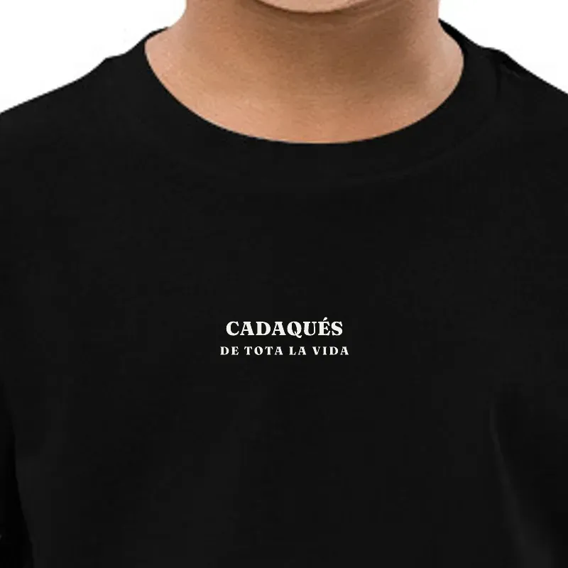 Nen amb samarreta blanca amb el nom del seu poble estampat al pit.
