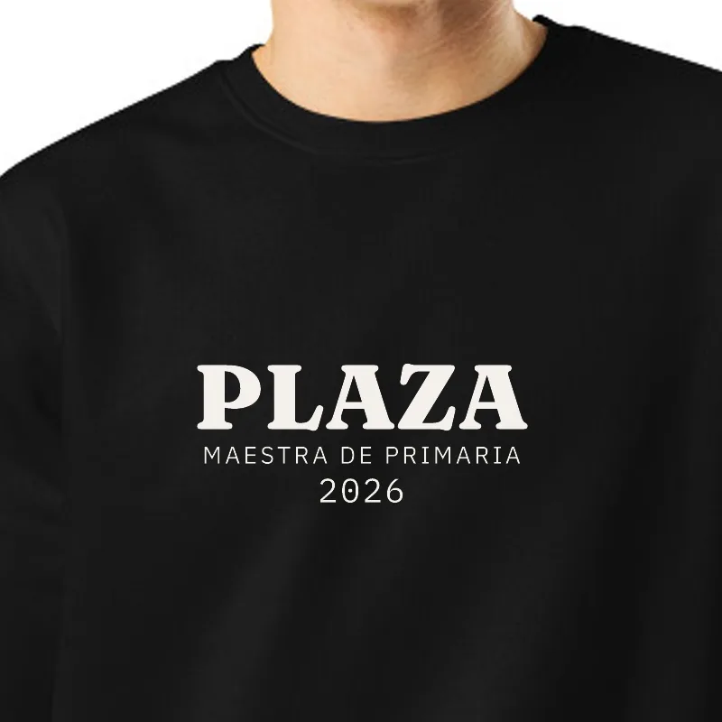 Chico con sudadera negra, encuadre al sello: PLAZA · MAESTRA DE PRIMARIA